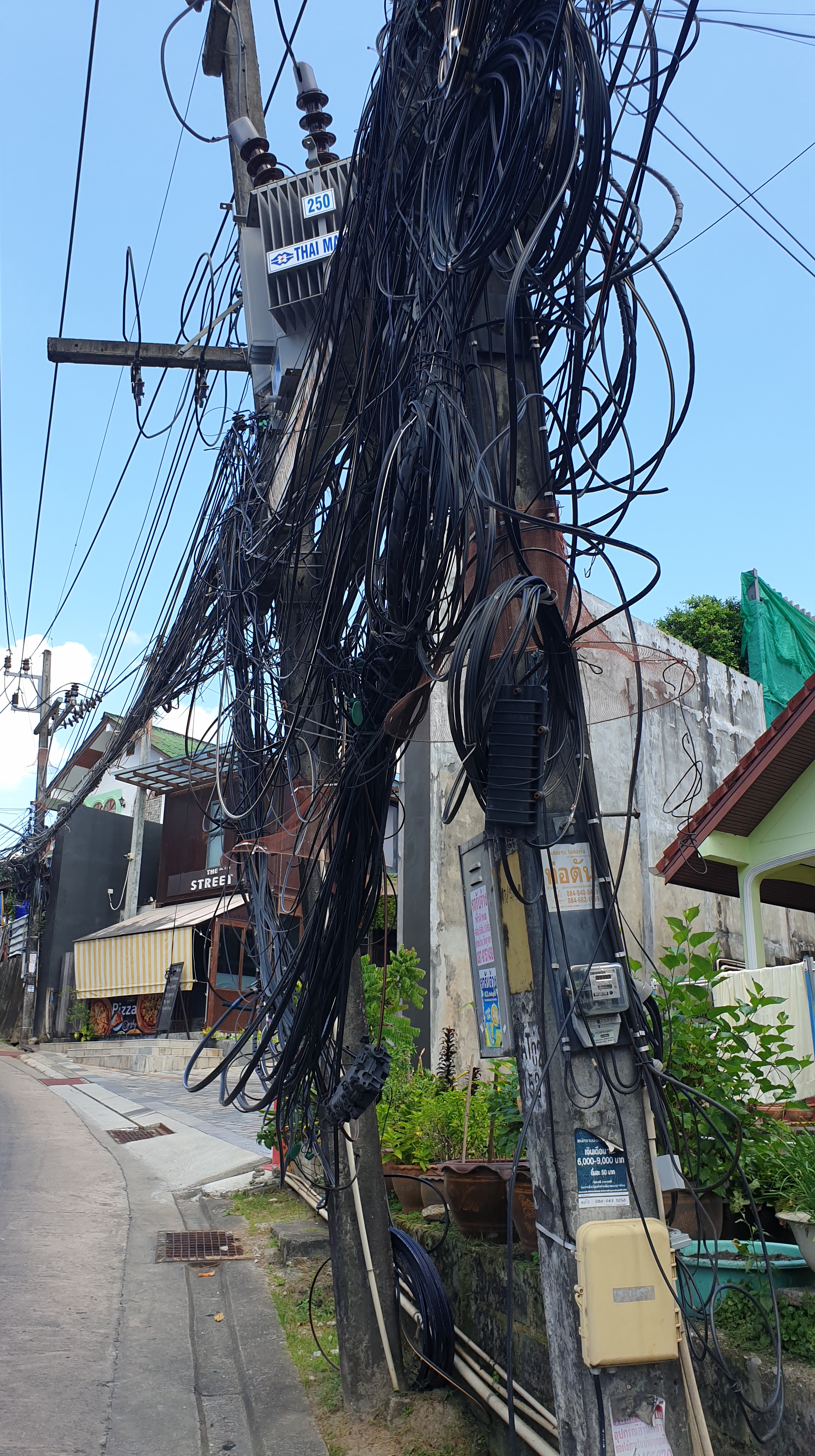 Lots of telecommunications cables hanging from pole in Thailand